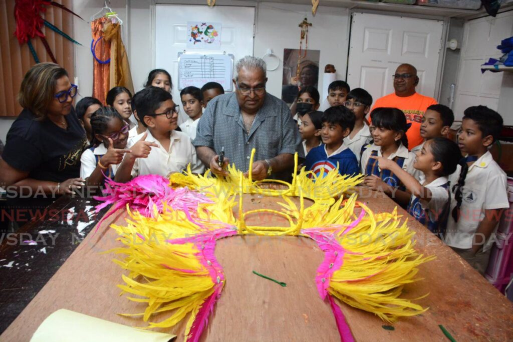 Masman Ivan Kalicharan, centre, gives the students a step-by-step demonstration on making a head piece.  -  Photos by Innis Francis