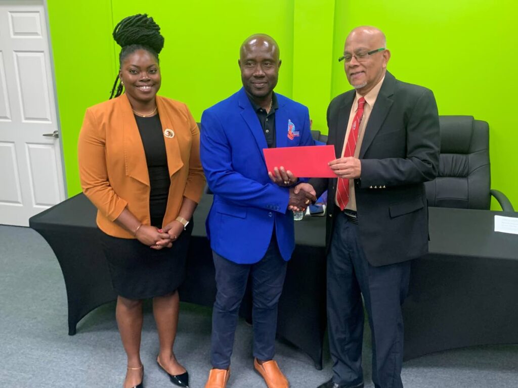 Trinidad and Tobago Cricket Board Azim Bassarath president, right, presents a cheque for the inaugural Earl Arthur Memorial Tournament to Kerwin John, president of the Tobago Cricket Association. On the left is Dr Renee Arthur, daughter of Earl Arthur. - 