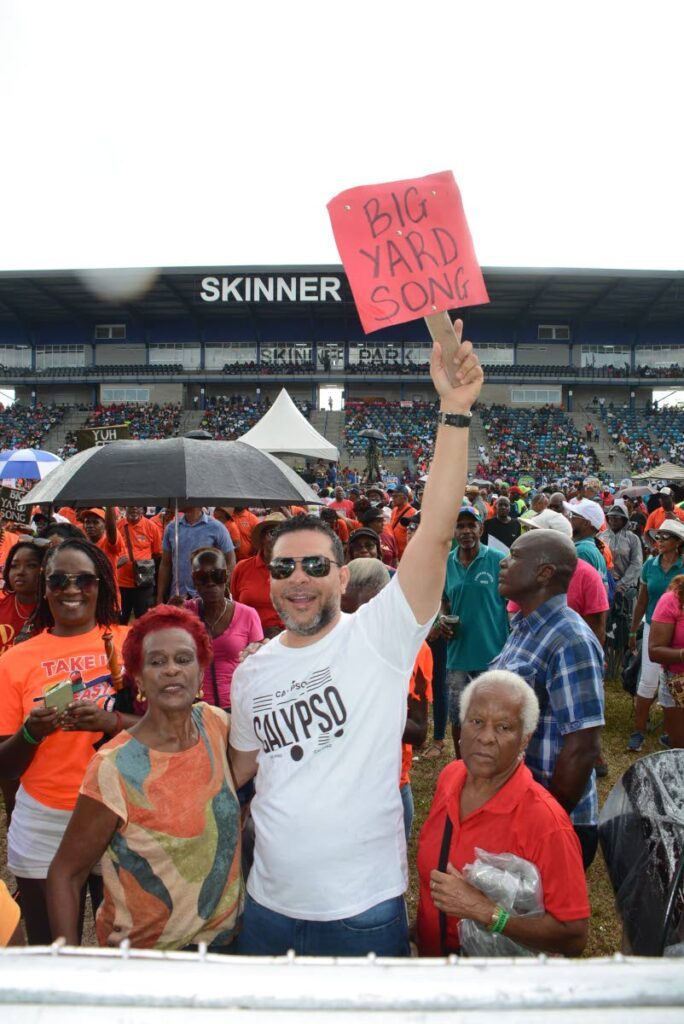 Tourism Minister Randall Mitchell hugs a patron and waves for a calypso rendition he approves of at TUCO’s Calypso Fiesta at Skinner Park, San Fernando on February 22. - Photos by Innis Francis