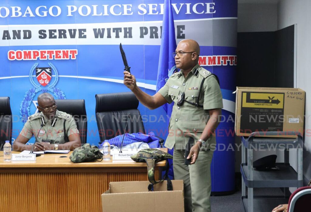 ASP Richard Smith shows reporters at a police press briefing a knife seized by police from someone entering a Carnival event. Looking on is acting Police Commissioner Junior Benjamin. - Photo by Faith Ayoung