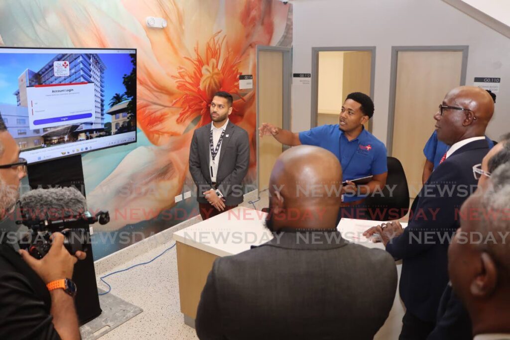 A health information technician, centre, explains to the Prime Minister, right, how the registration system works as other government and health officials look on during a tour Port of Spain General Hospital Central Block on March 10. - Photo by Ayanna Kinsale