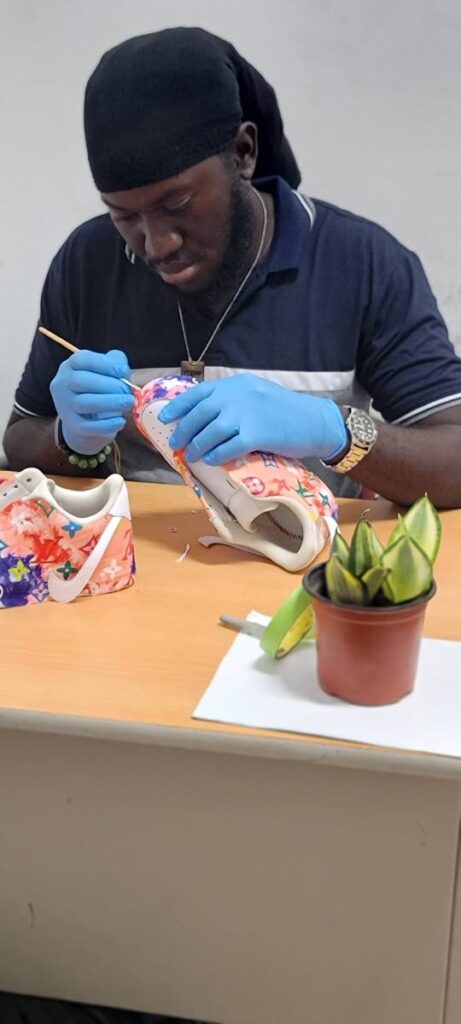 Shaquille Toby works on transforming a sneaker into a work of art. - 