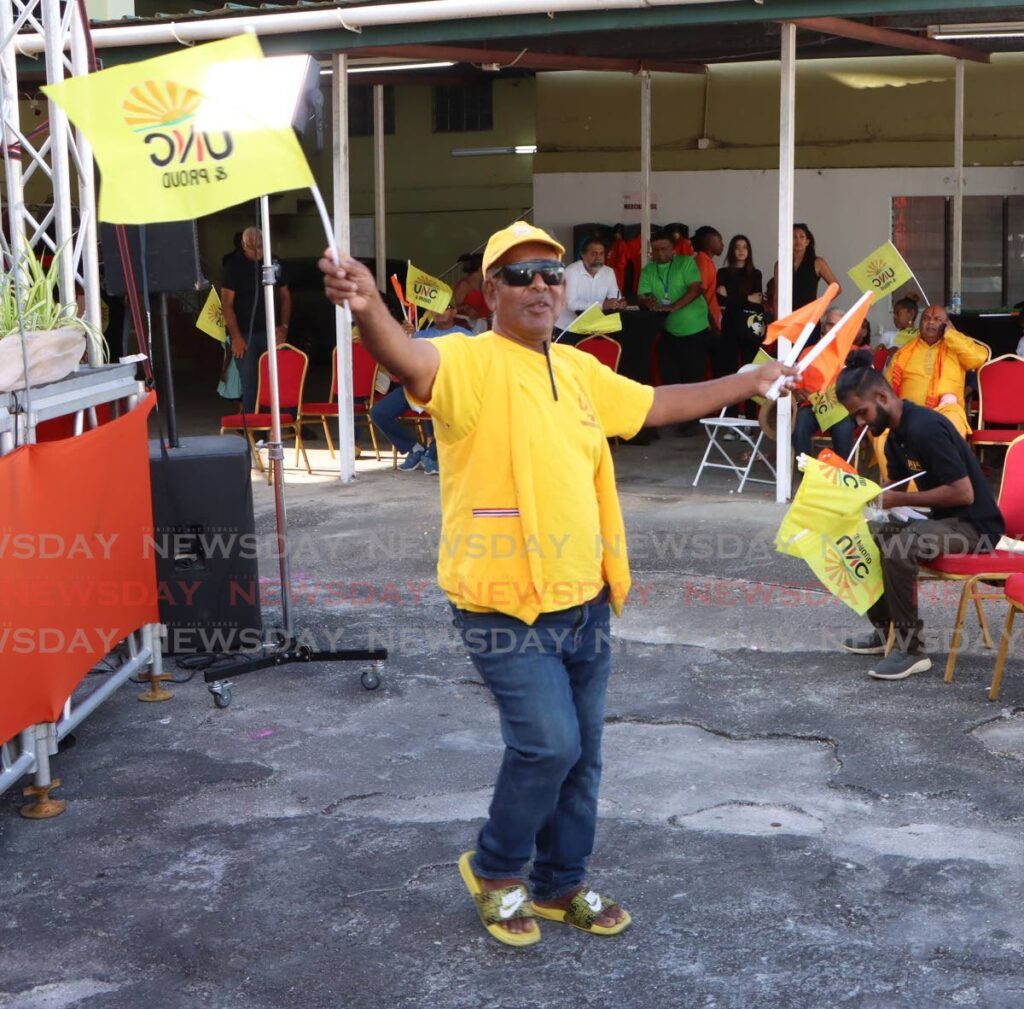 A UNC supporter waves his party's and PEP's flags, at a political meeting held by PEP, at Bamboo #1 St Joseph on March 22. - Photos by Angelo Marcelle